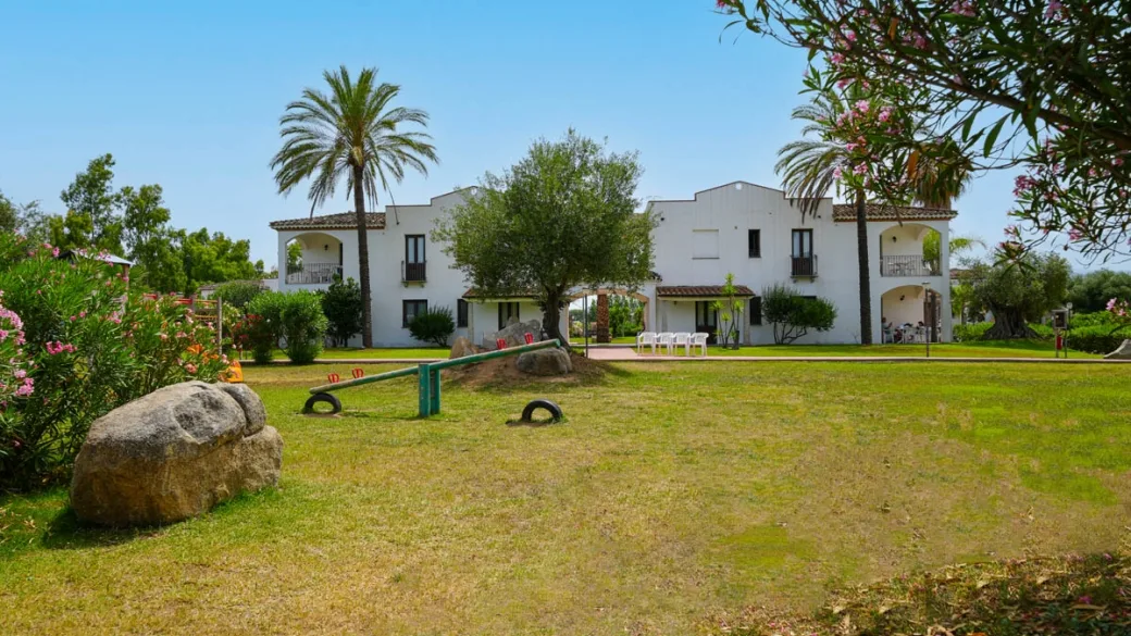 Giardino del resort con palme, prato verde e area giochi per bambini
