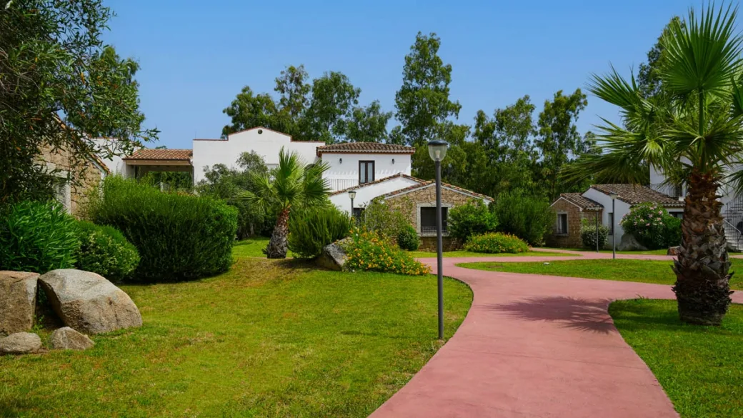 Giardino del resort con vialetto, palme ed edifici in pietra