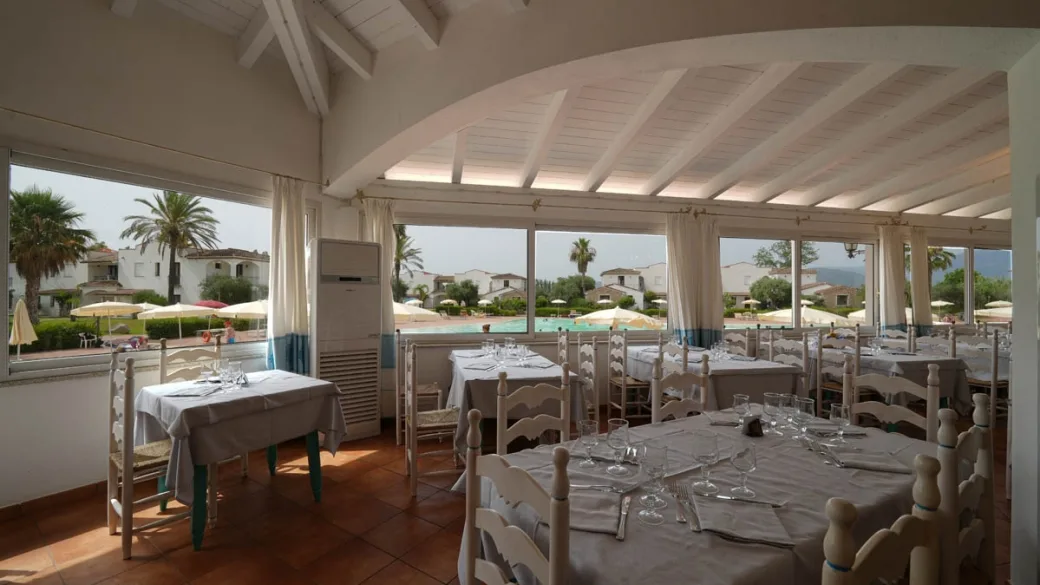 Sala ristorante con tavoli apparecchiati e vista sulla piscina