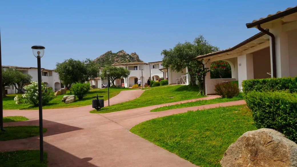 Vialetti del resort tra gli edifici bianchi con giardini e montagne sullo sfondo