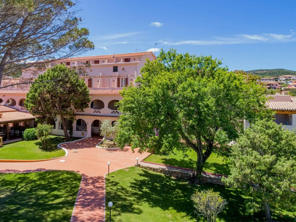 Edificio dell'hotel con portici e giardino curato con alberi