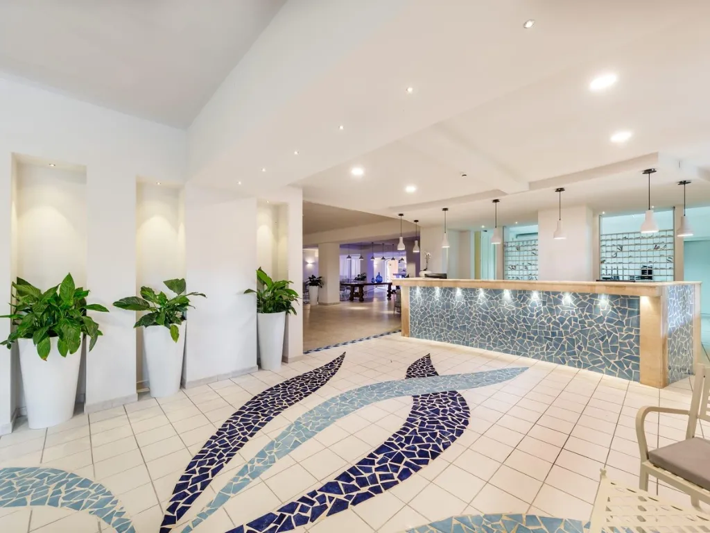 Reception dell'hotel con pavimento a mosaico blu e piante