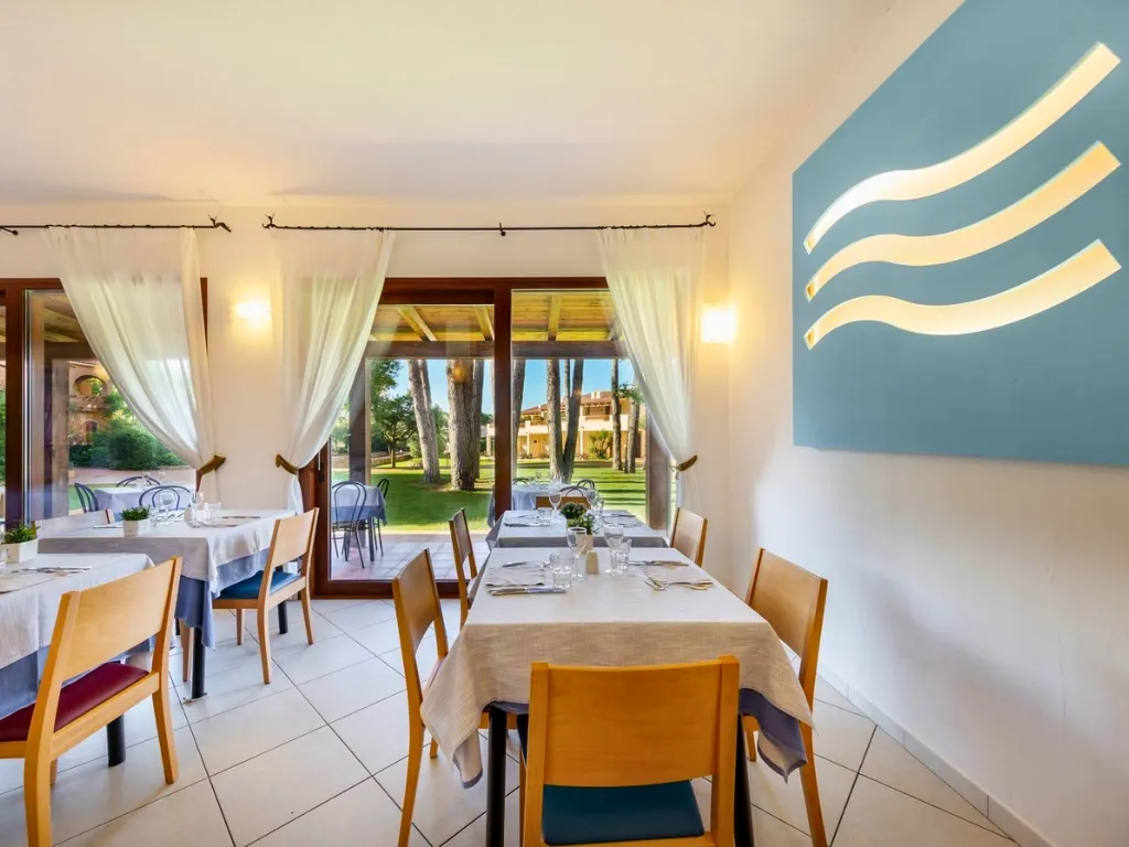 Sala ristorante con tavoli apparecchiati e vista sul giardino