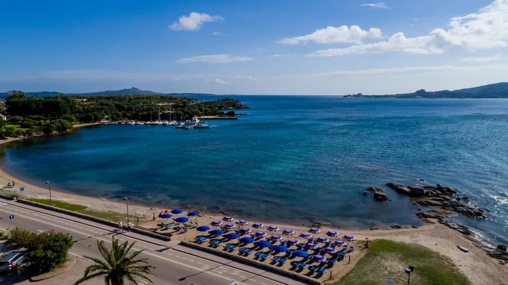 Veduta aerea della spiaggia con ombrelloni blu e porticciolo
