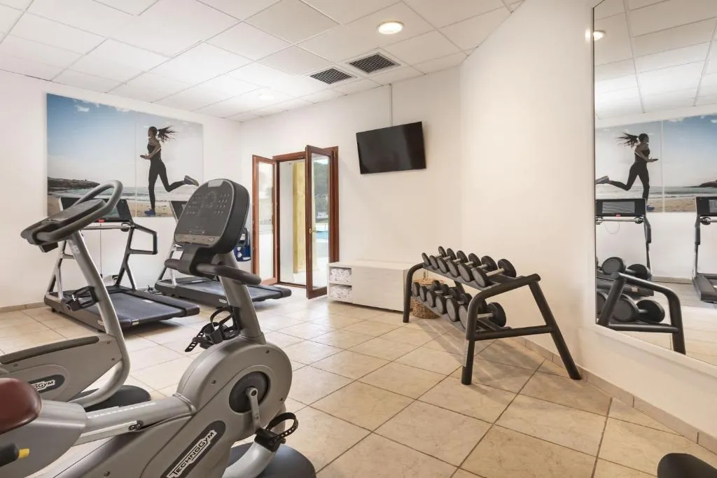 Palestra con tapis roulant, cyclette e pesi davanti a uno specchio