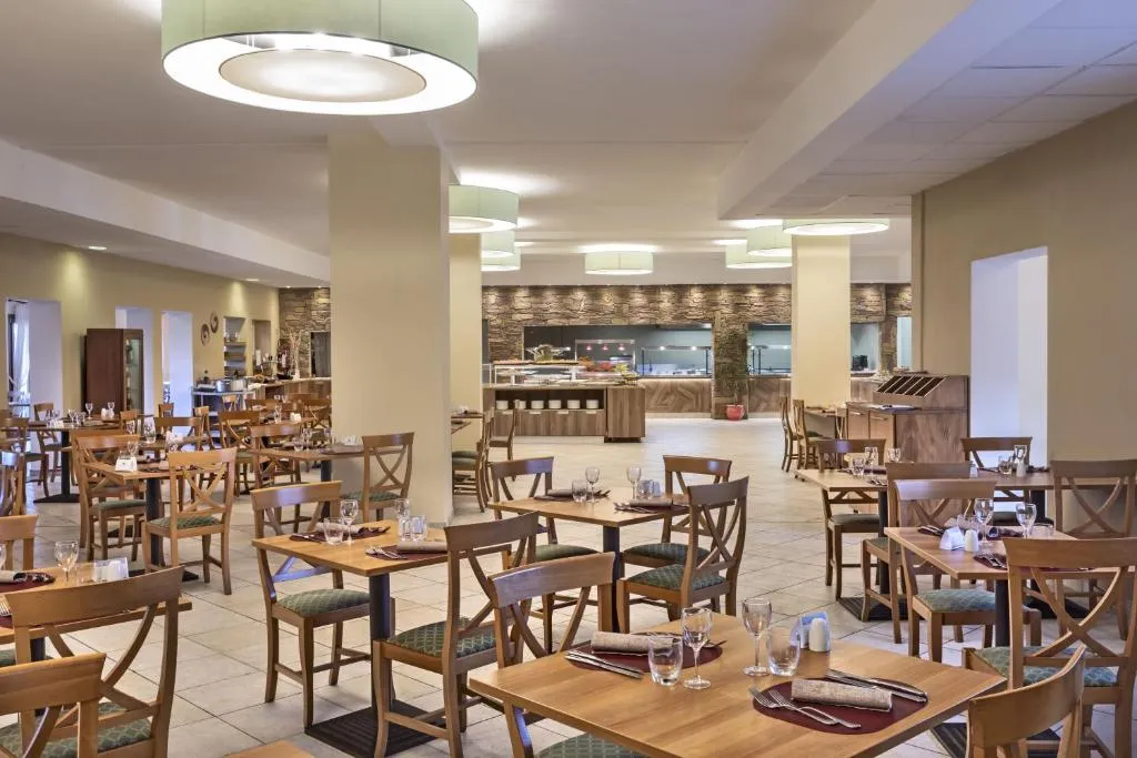 Sala ristorante interna con tavoli in legno apparecchiati e buffet sullo sfondo