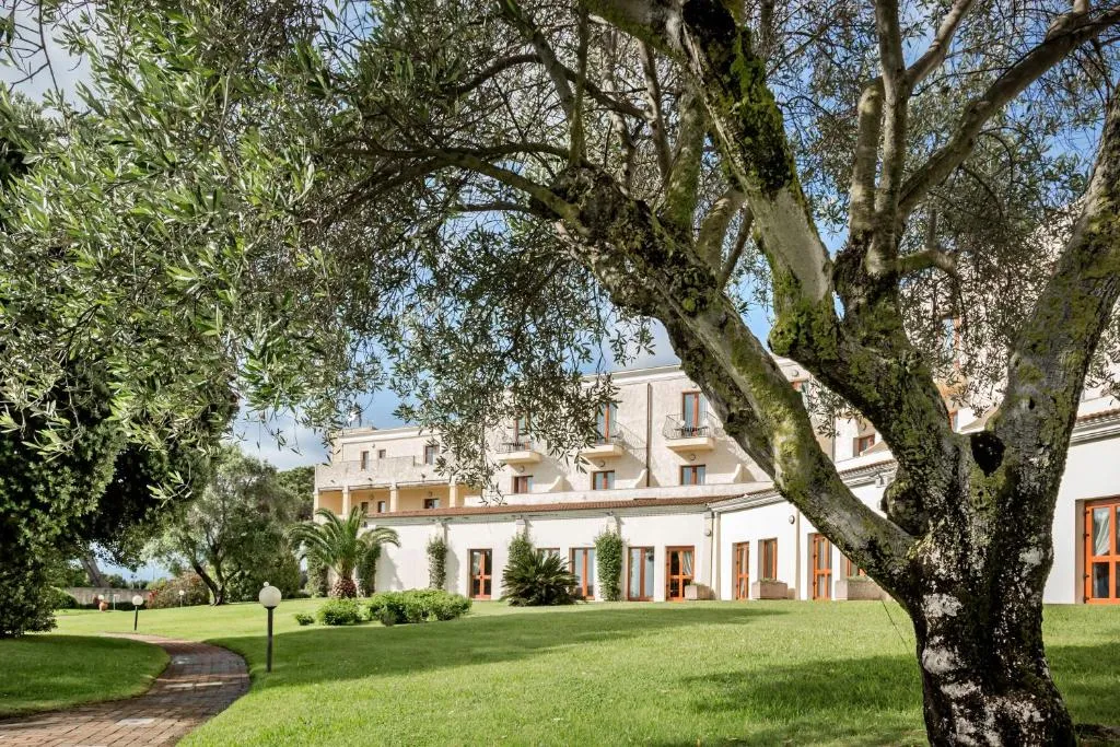 Giardino con ulivi e vialetto davanti alla facciata dell'hotel