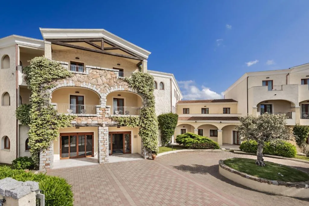 Cortile dell'hotel con edifici in pietra, archi e piante rampicanti