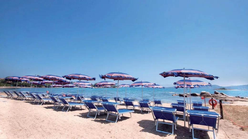 Spiaggia con lettini e ombrelloni a righe sul mare azzurro