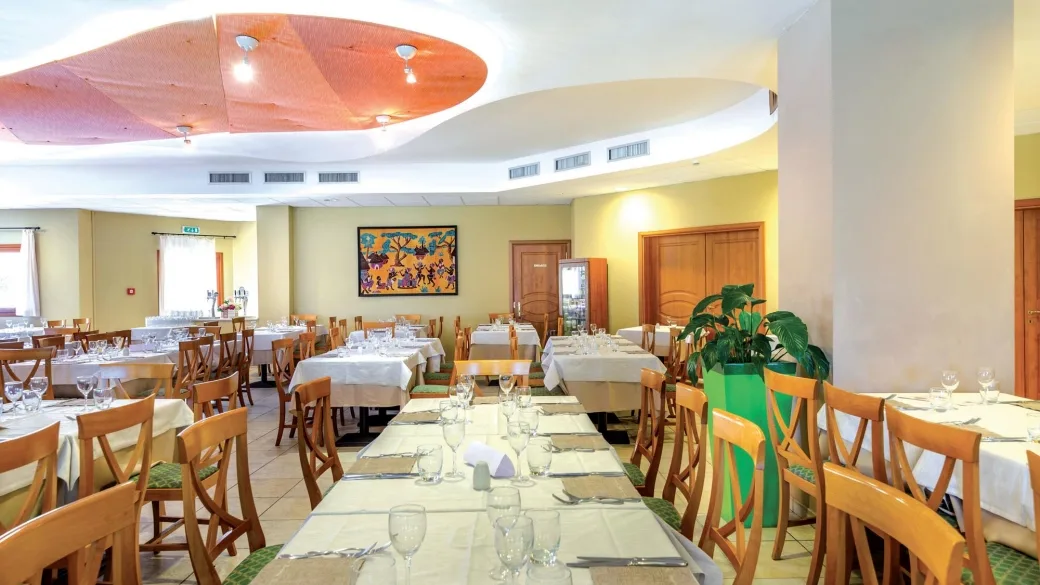 Sala ristorante con tavoli apparecchiati con tovaglie bianche e quadro colorato