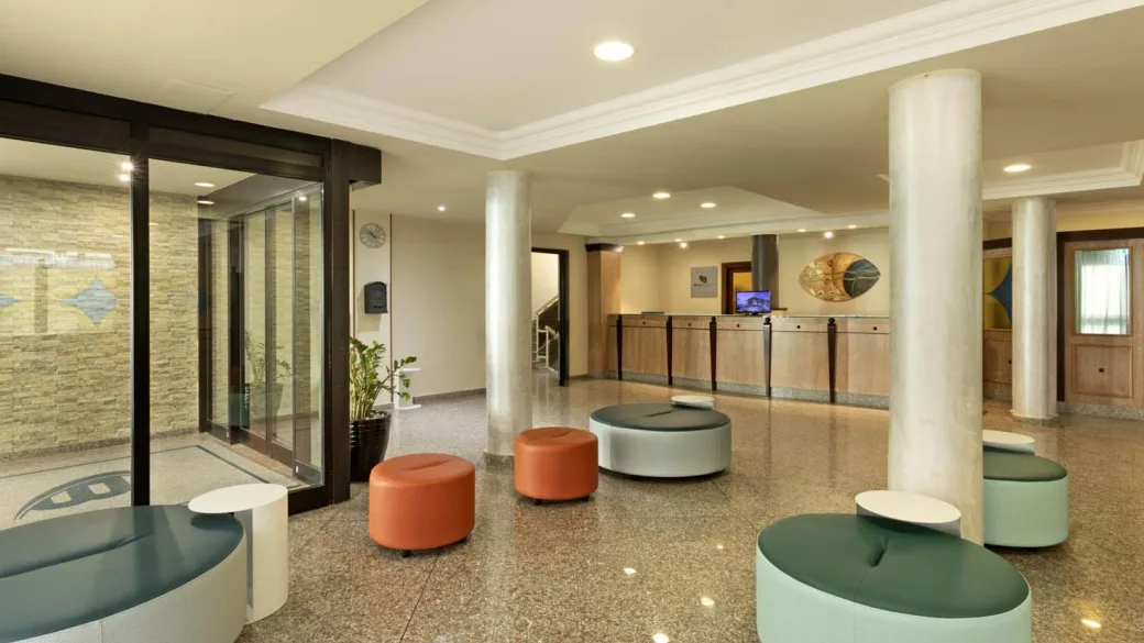 Hall dell'hotel con pavimento lucido, pouf colorati, colonne e reception