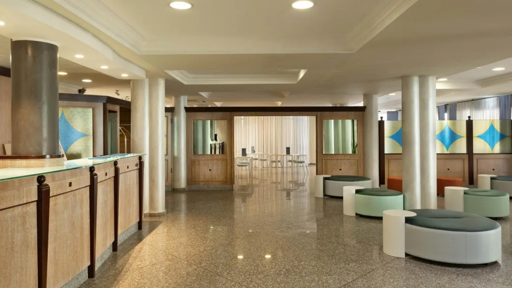 Reception e area lounge dell'hotel con colonne, pouf moderni e decorazioni colorate