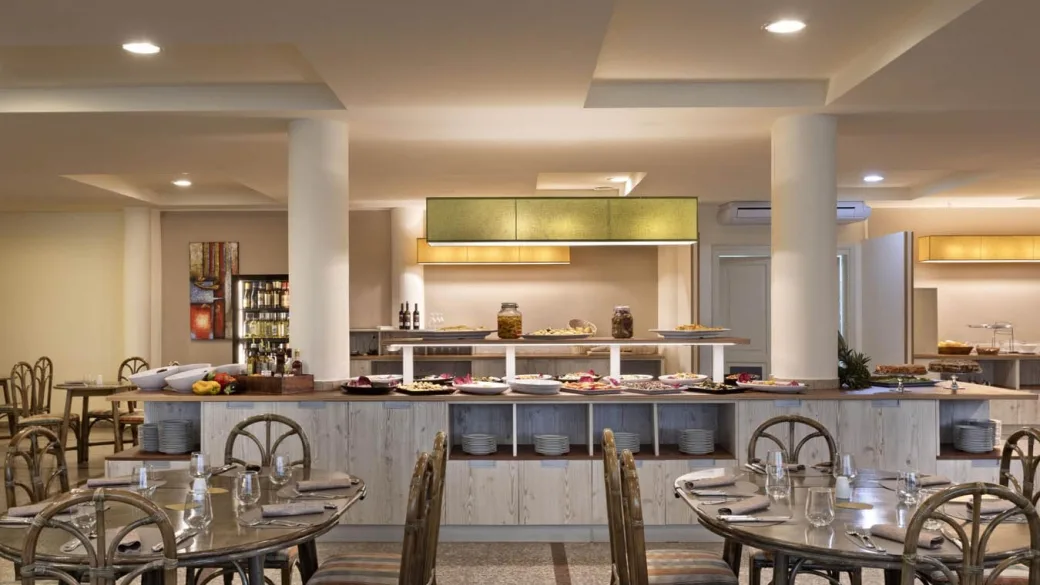 Sala ristorante con buffet ricco di piatti e tavoli apparecchiati