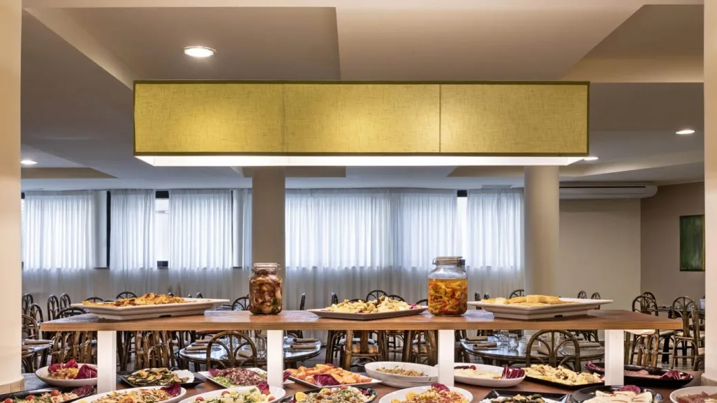Buffet del ristorante con ampia selezione di piatti e tavoli sullo sfondo