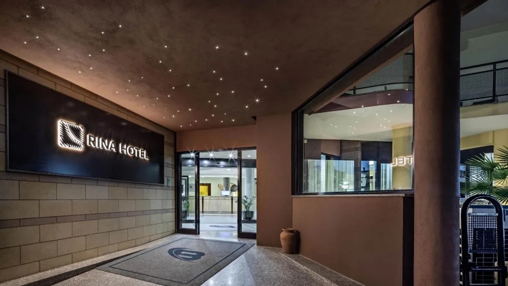 Ingresso del Rina Hotel con insegna luminosa e soffitto con luci a stella