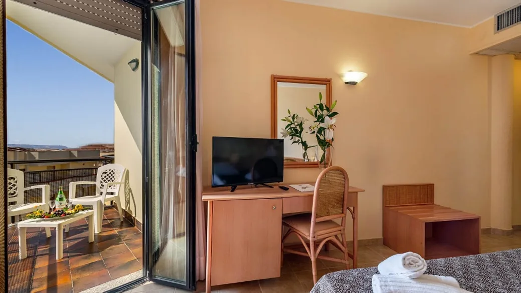 Dettaglio della camera con scrivania, TV e balcone con vista e tavolino