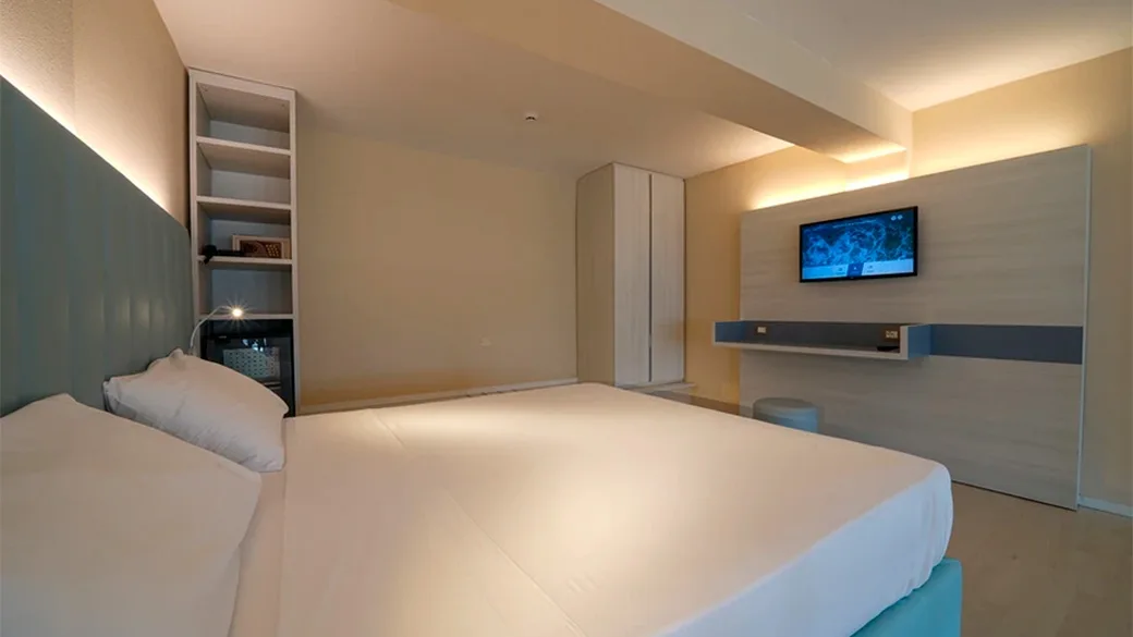 Camera moderna con letto matrimoniale, mensola con TV e libreria integrata