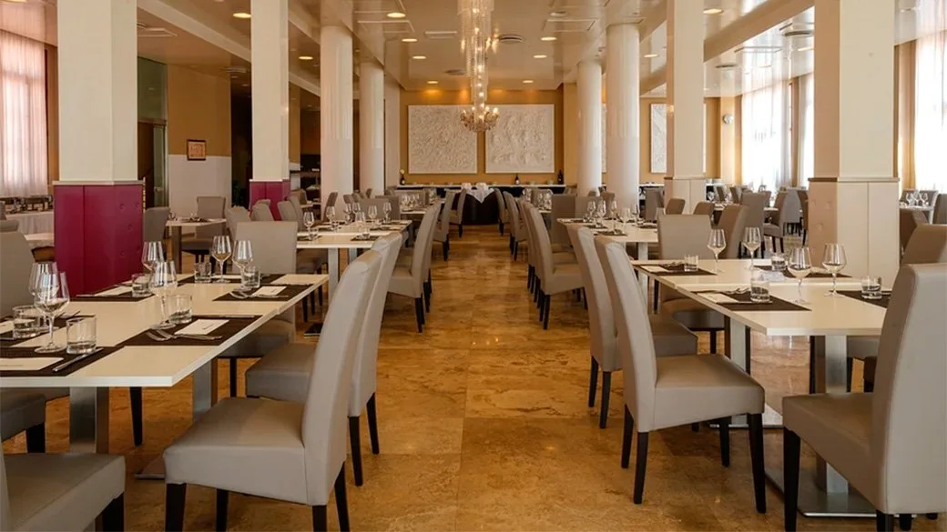 Sala ristorante elegante con tavoli apparecchiati, colonne bianche e lampadari di cristallo