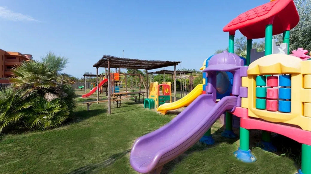 Area giochi per bambini nel giardino con scivoli colorati e strutture in legno