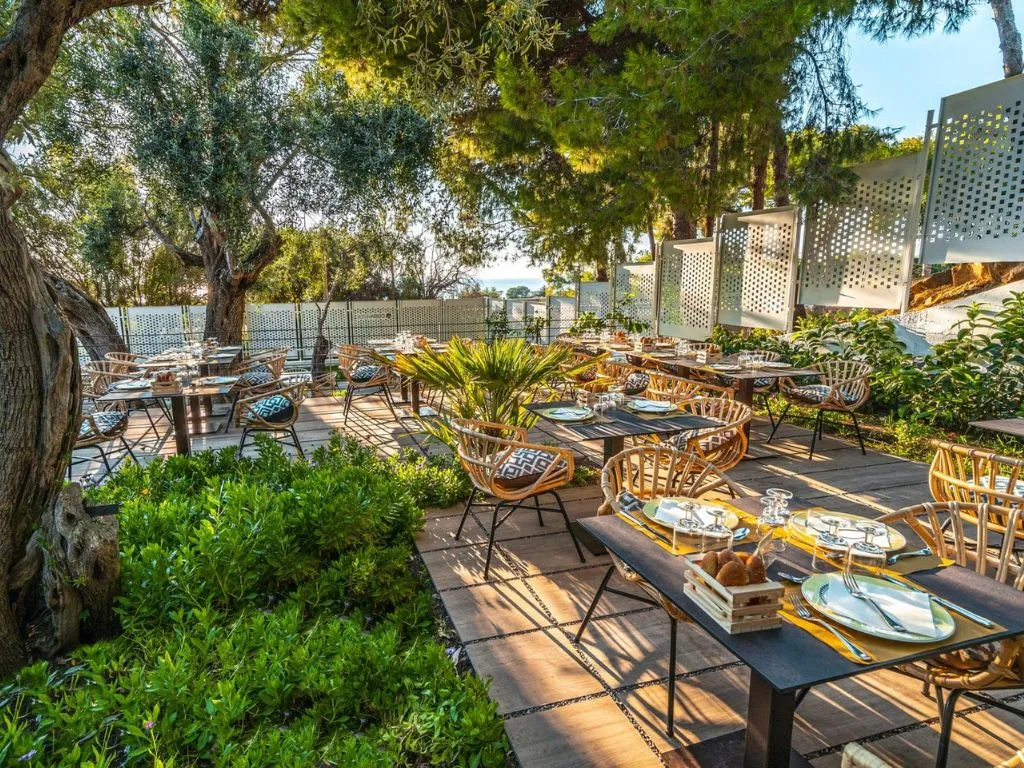 Ristorante all'aperto immerso nel verde con tavoli apparecchiati tra gli alberi