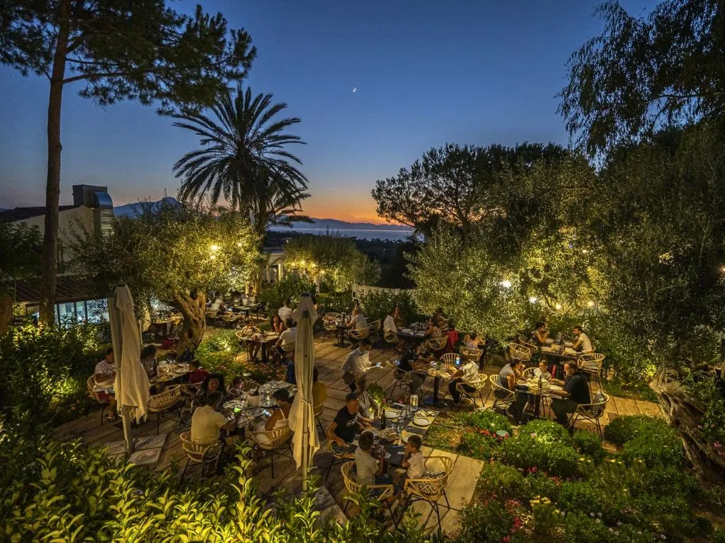 Ristorante nel giardino illuminato al tramonto con ospiti a cena