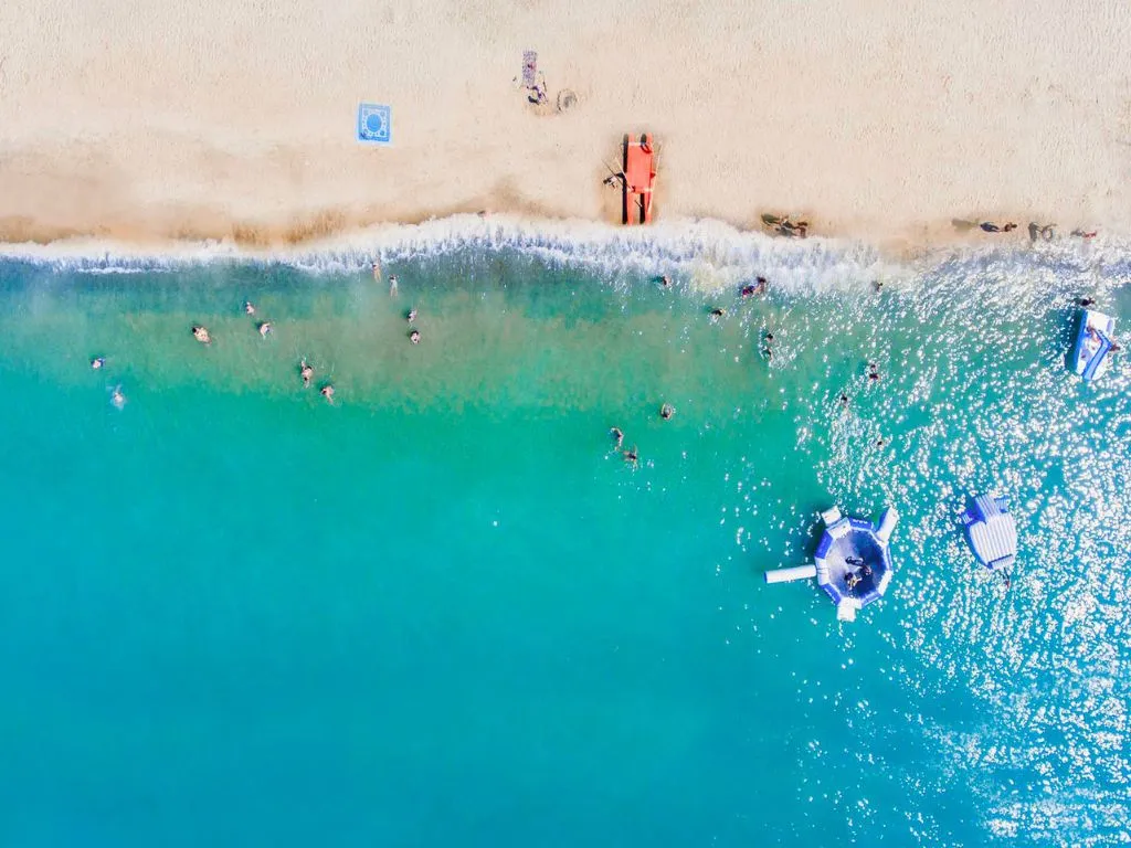 Vista aerea della spiaggia e del mare turchese con bagnanti e gonfiabili