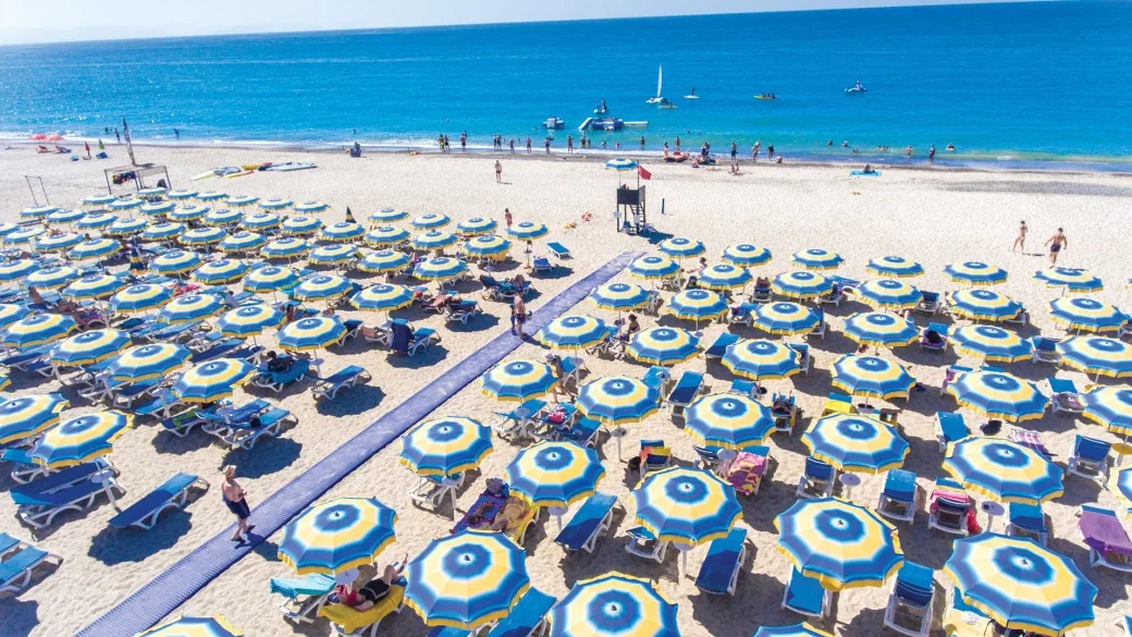 Spiaggia attrezzata con ombrelloni gialli e blu e mare turchese