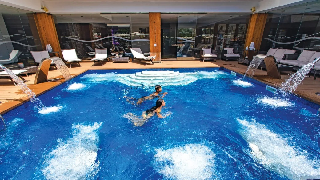 Piscina interna con idromassaggio e cascate d'acqua in area benessere