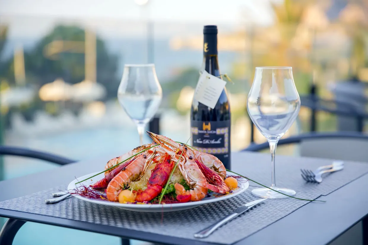 Piatto di crostacei e gamberi con bottiglia di vino su tavolo con vista sul mare
