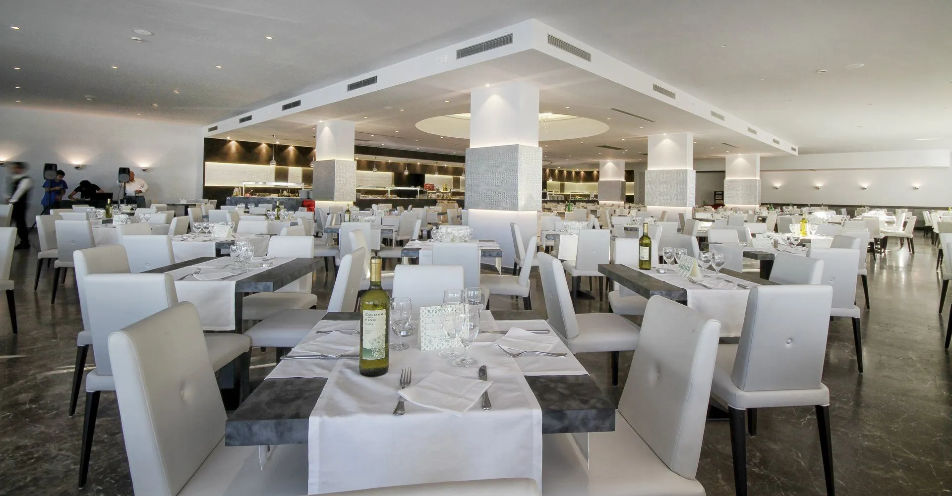 Ampia sala ristorante moderna con tavoli apparecchiati e sedie bianche