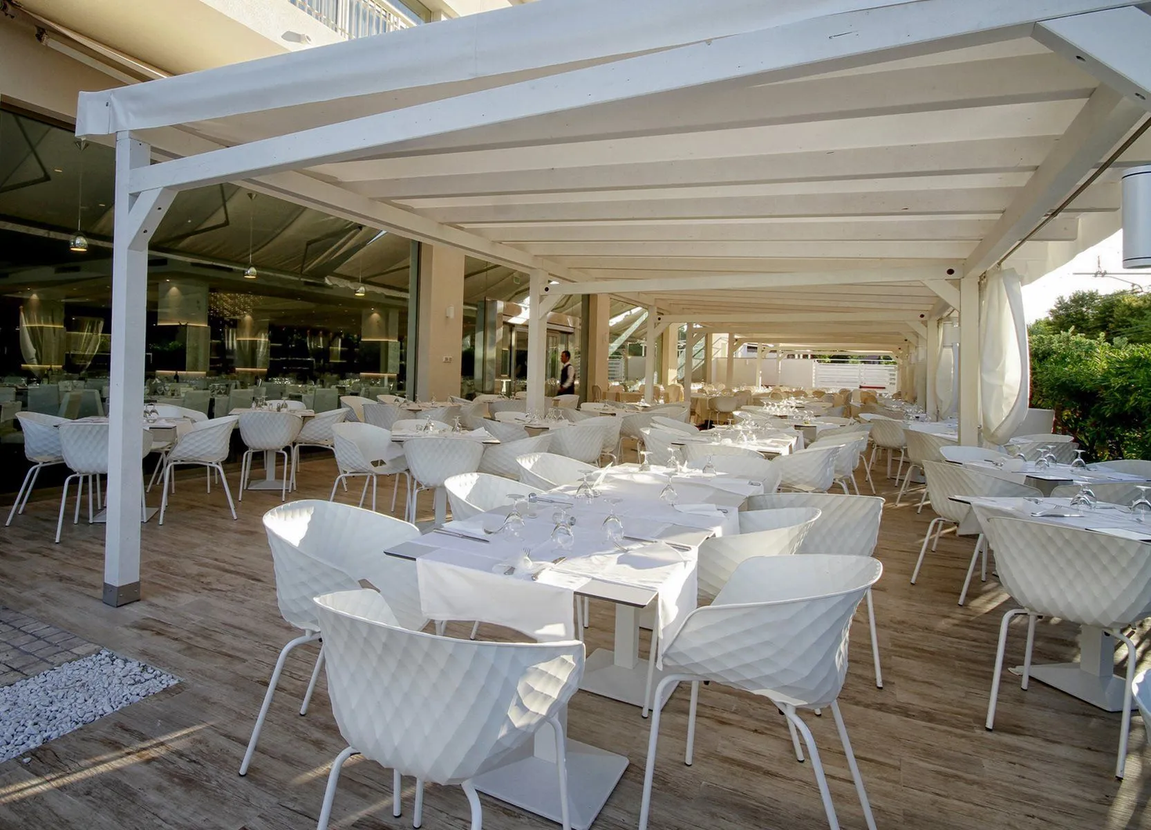 Terrazza ristorante all'aperto con pergolato bianco e tavoli apparecchiati eleganti