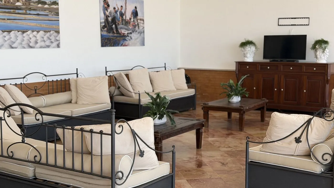 Salottino interno con divani in ferro battuto, cuscini beige e TV