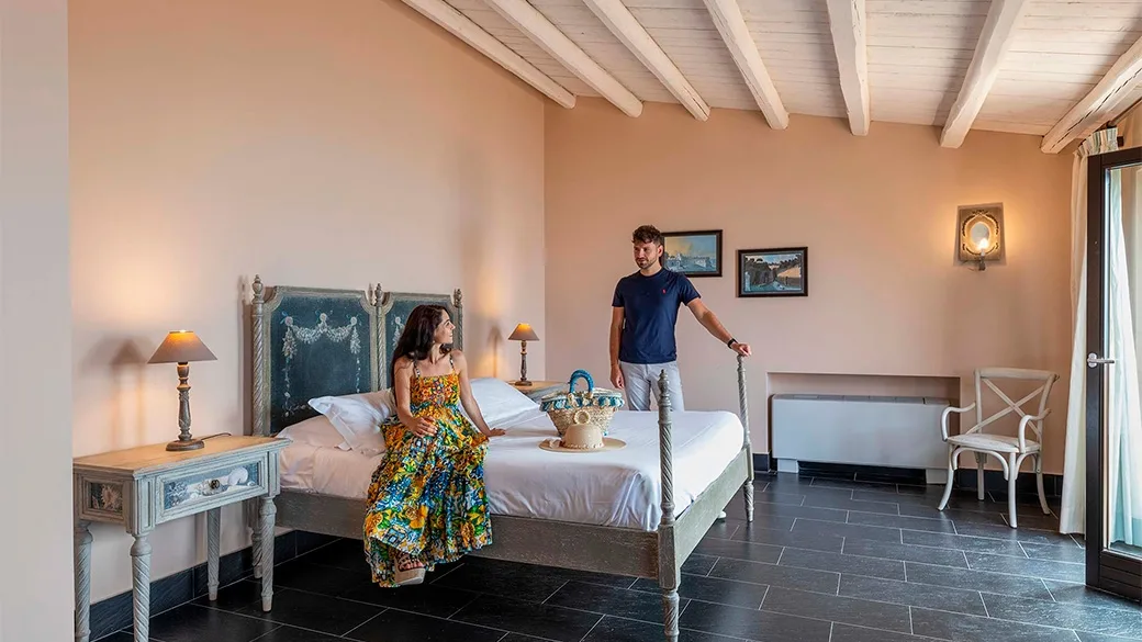 Camera elegante con letto in stile provenzale, soffitto a travi e coppia di ospiti