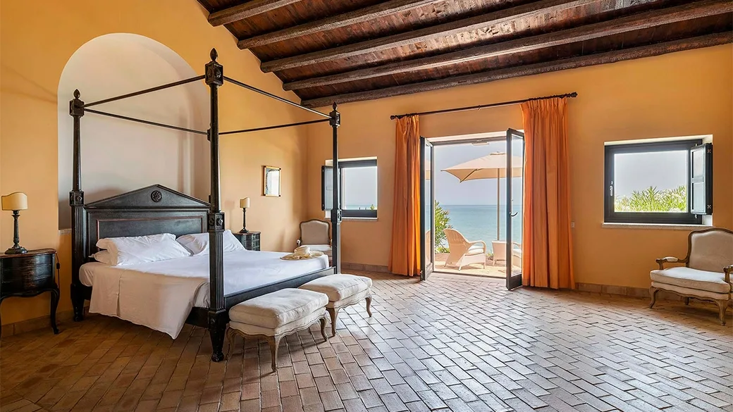 Camera spaziosa con letto a baldacchino, soffitto a travi e terrazza vista mare