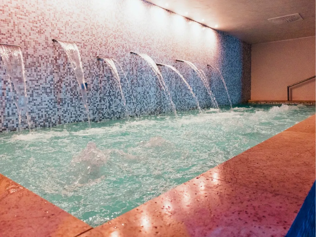 Percorso Kneipp con cascate d'acqua su parete a mosaico nella spa