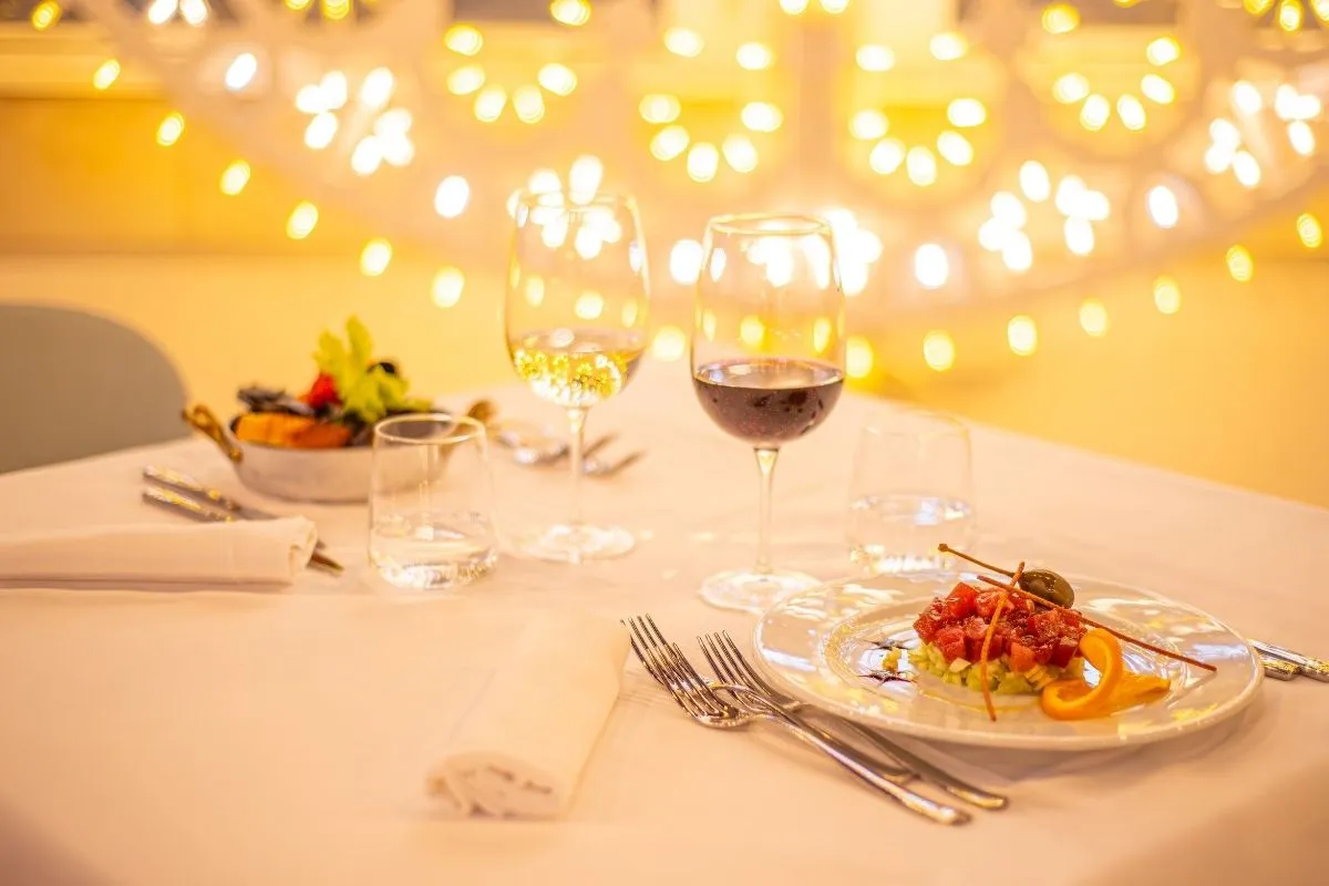 Tavolo con cena romantica, tartare e calici di vino con luci soffuse