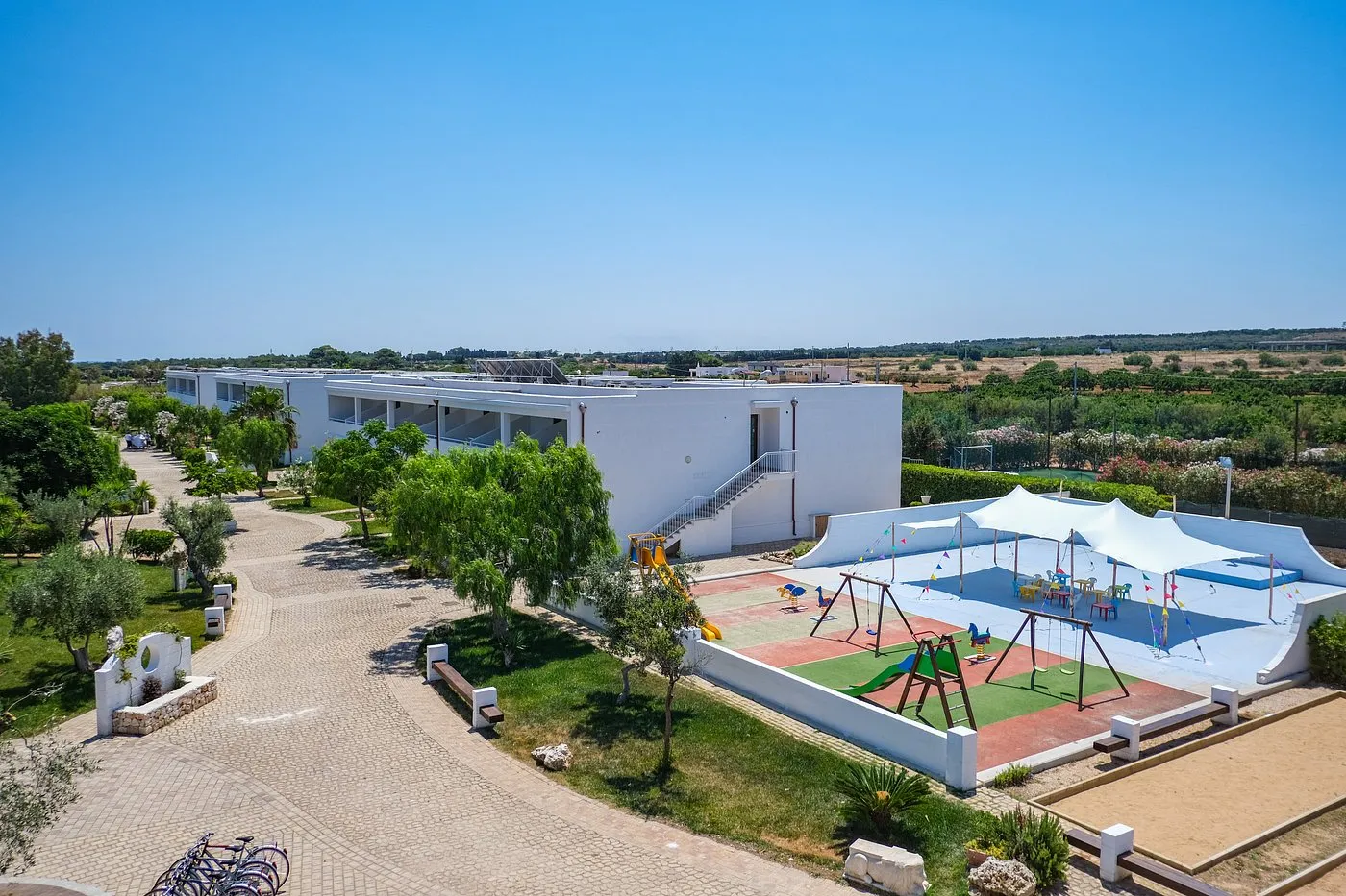 Area giochi per bambini con struttura ombreggiata e edificio del resort