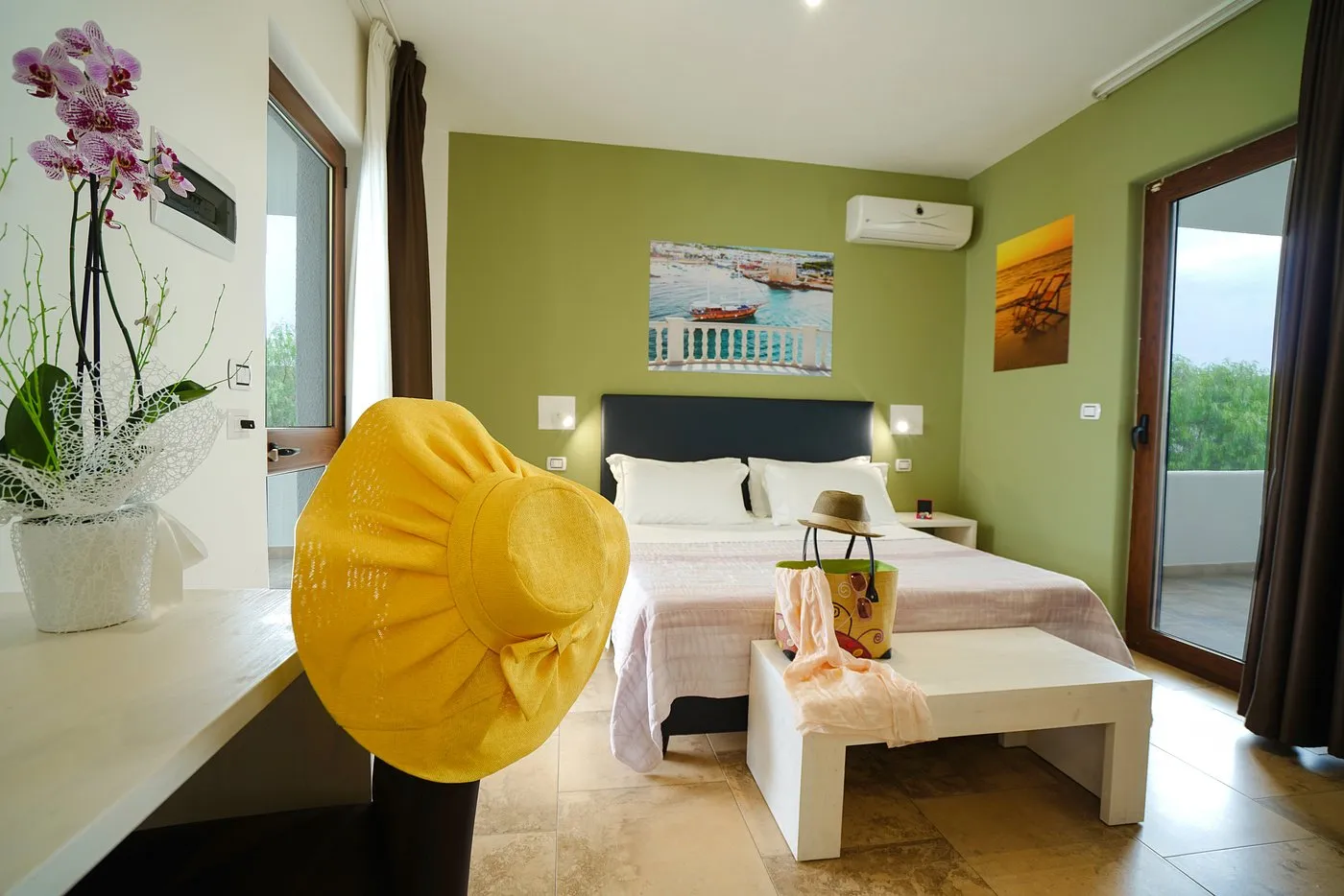 Camera matrimoniale con parete verde, cappello giallo e accesso al balcone