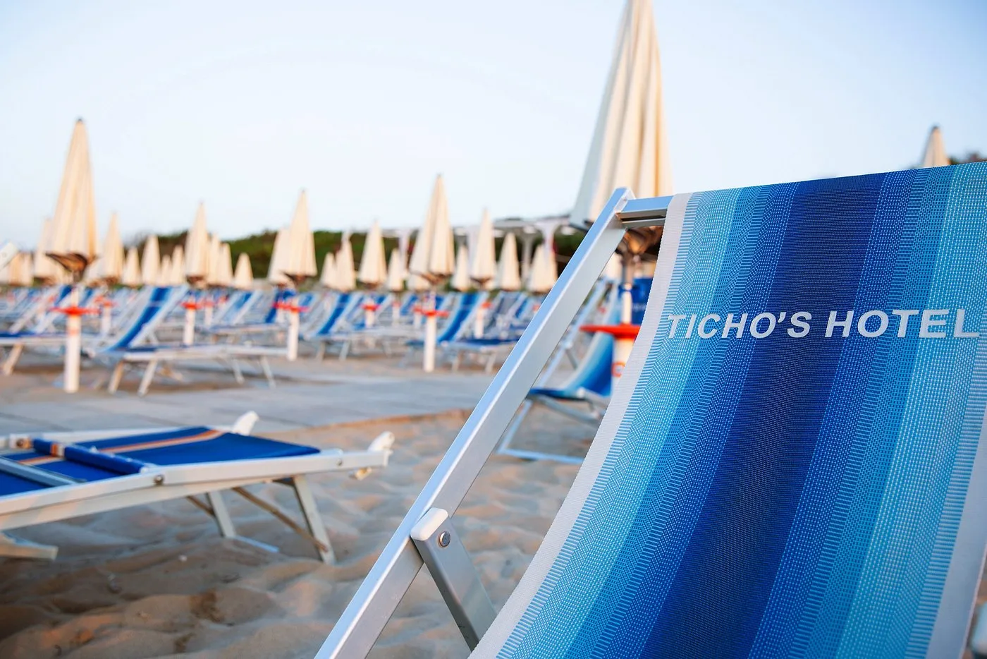Lettino con logo Ticho's Hotel sulla spiaggia al tramonto
