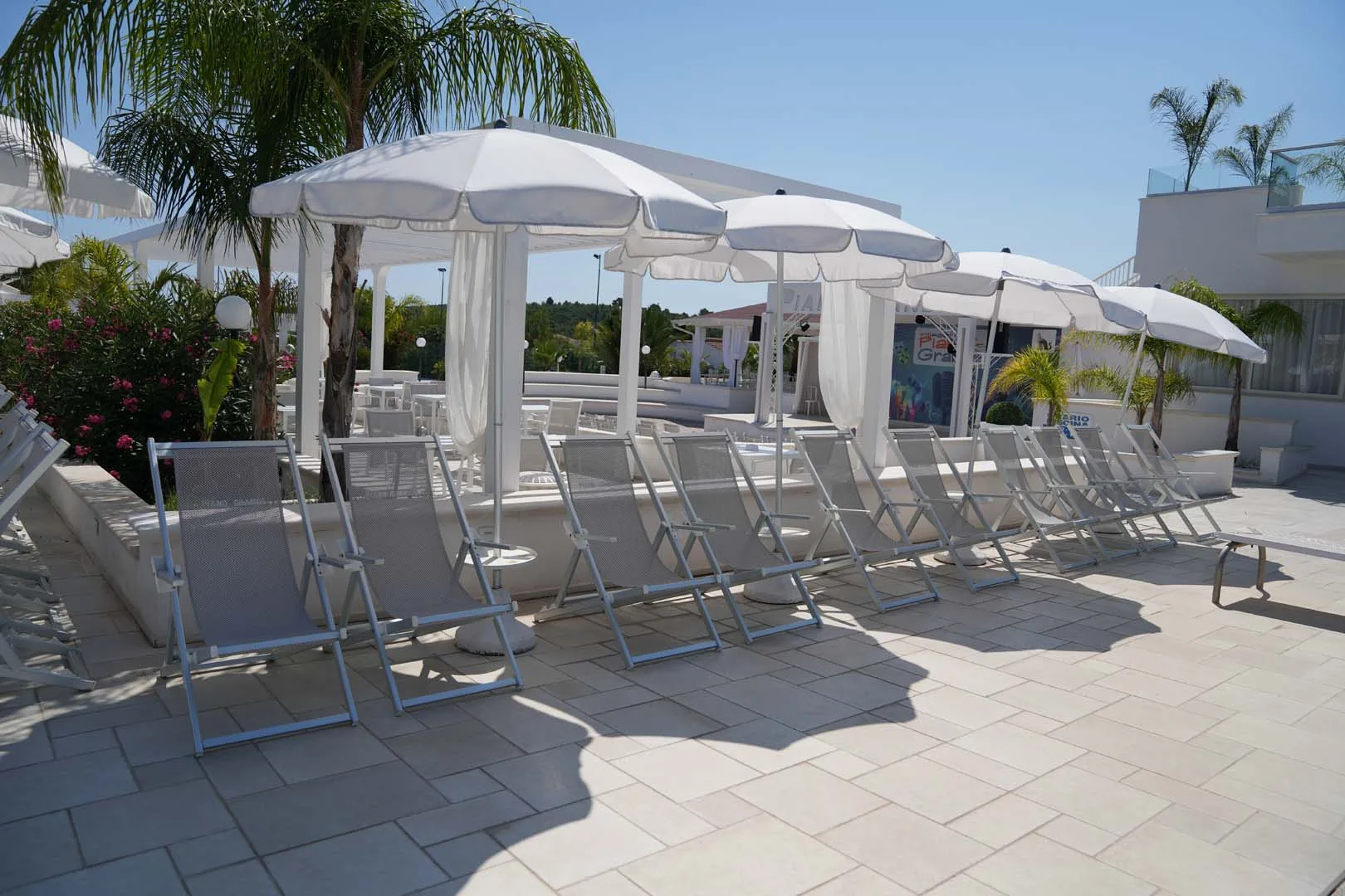Lettini e ombrelloni bianchi sulla terrazza solarium accanto al bar