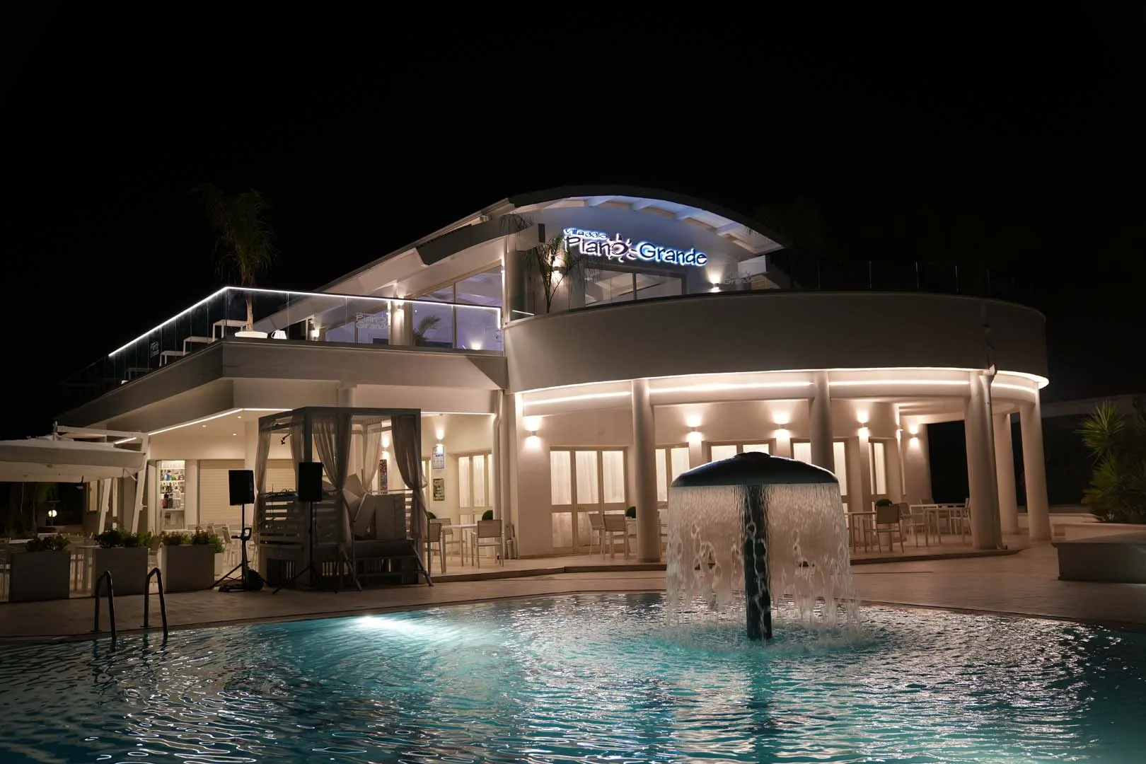 Edificio principale del villaggio illuminato di notte con fontana in piscina