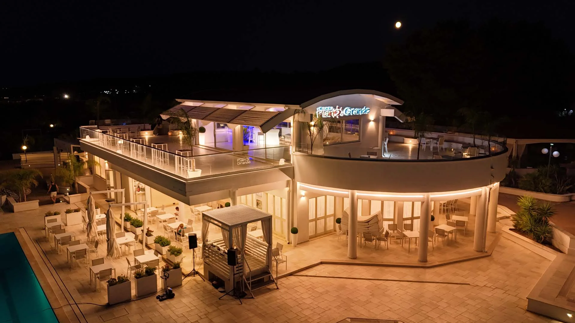 Edificio del villaggio illuminato di notte con terrazza panoramica e luna
