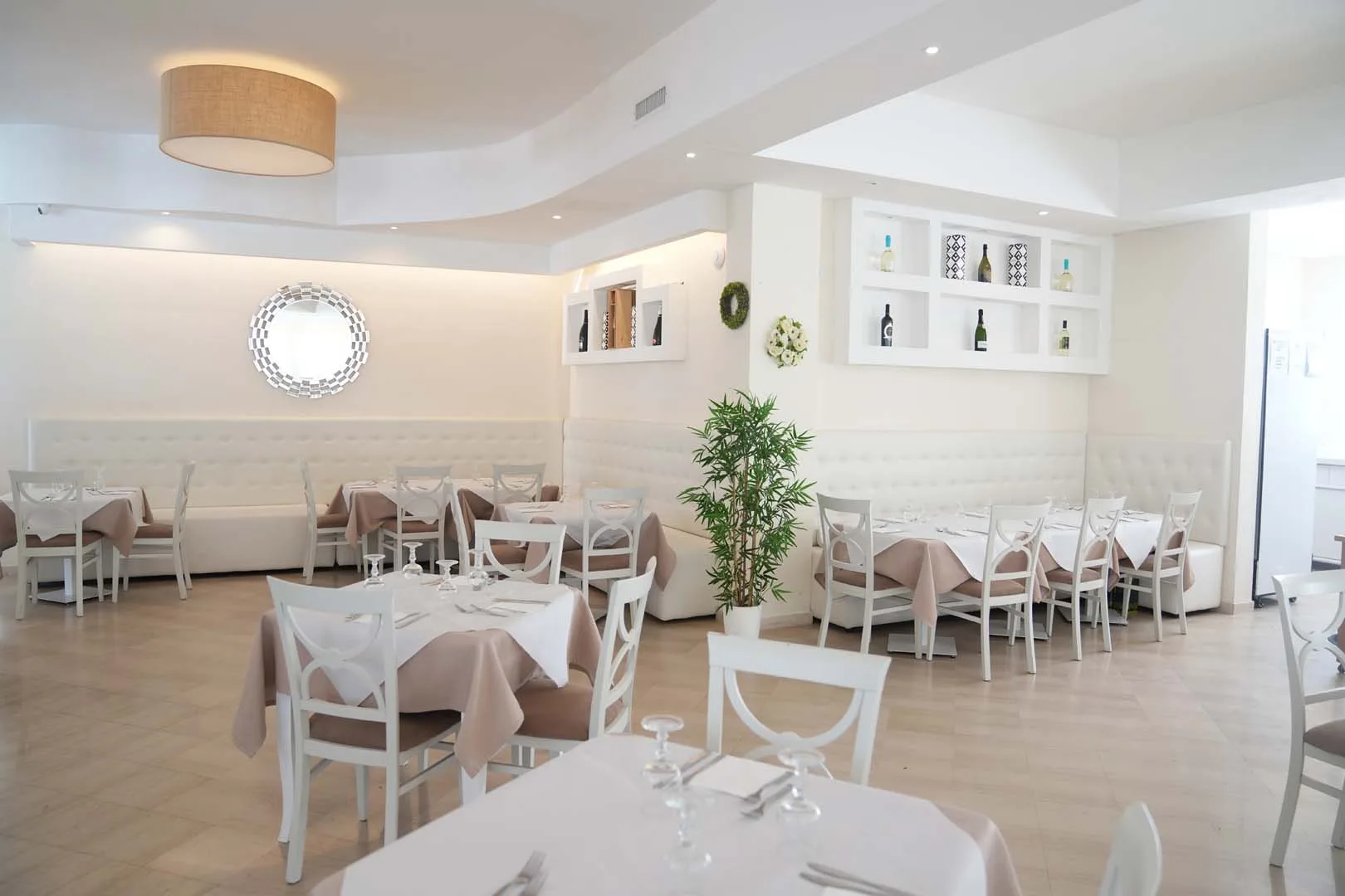 Sala ristorante interna con tavoli apparecchiati e arredi bianchi eleganti