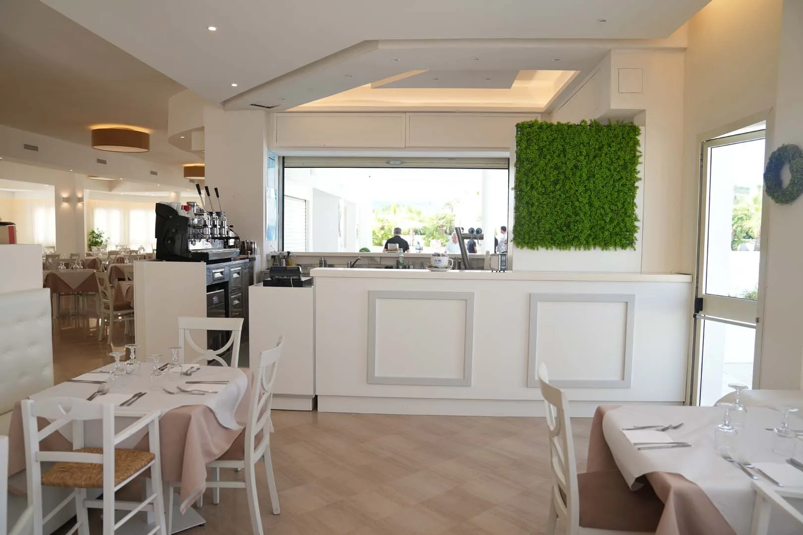 Interno del ristorante con bancone bar e parete verde decorativa