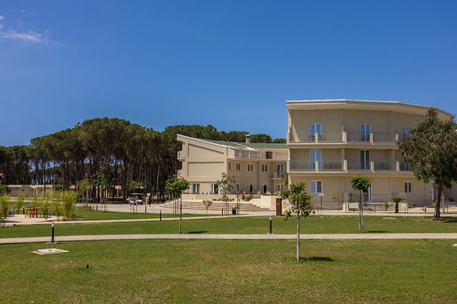 Edificio principale del resort dal design curvo circondato da prato verde e pineta