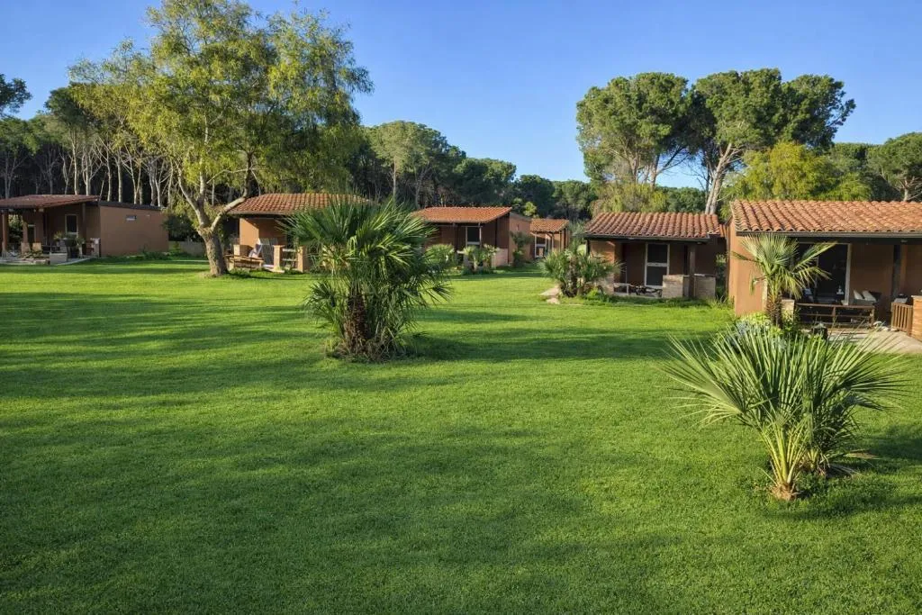 Bungalow del resort immersi in un ampio prato verde con palme e pineta