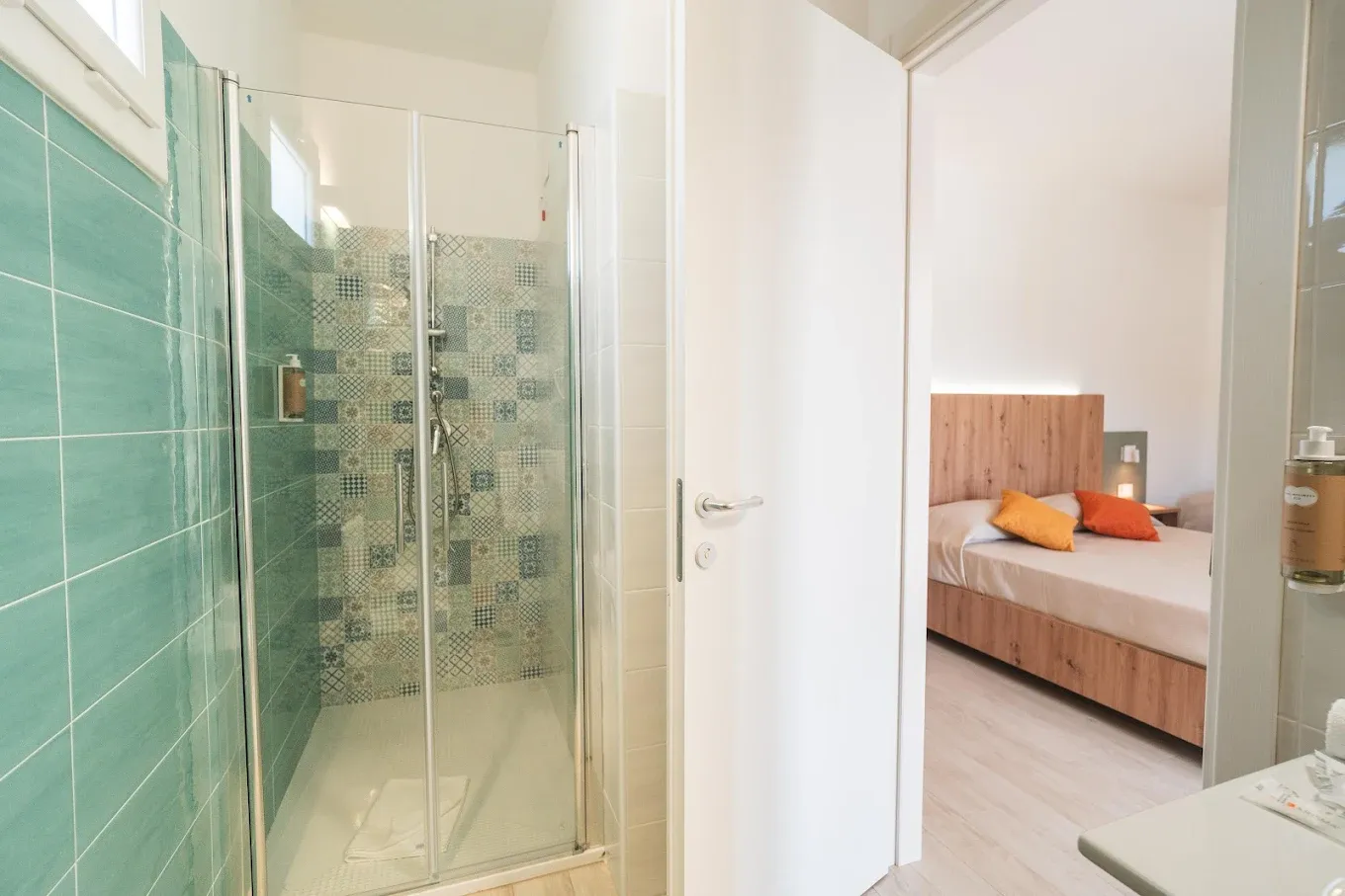 Bagno della camera con doccia, piastrelle decorative e vista sul letto