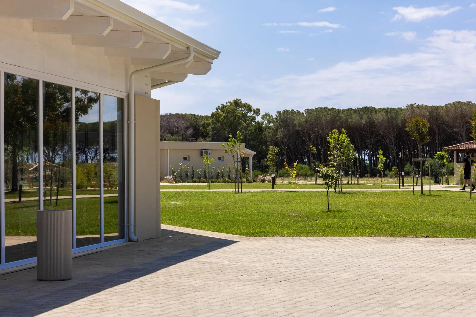 Terrazza pavimentata con grande vetrata affacciata sul prato e la pineta