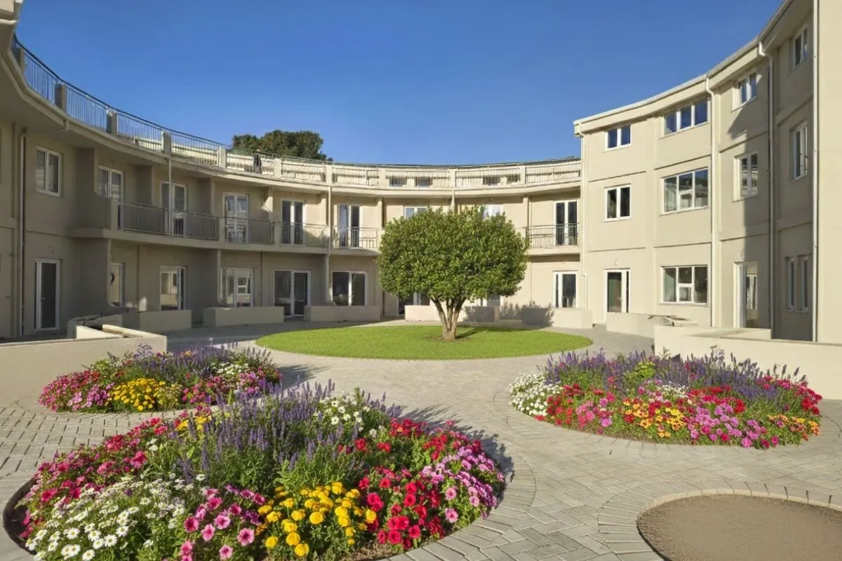 Cortile interno curvo del resort con aiuole fiorite colorate e albero centrale