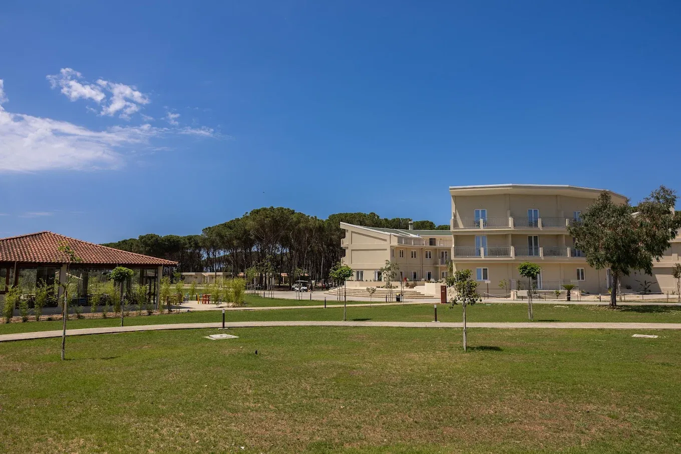 Veduta degli edifici del resort con prato verde, gazebo e pineta